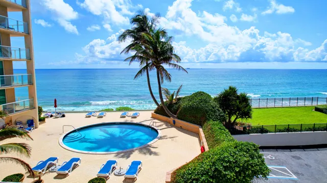 a view of a swimming pool with a table and chairs in front of house