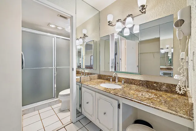 a bathroom with a granite countertop sink mirror and shower