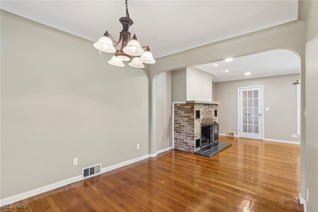 5097 Chillicothe Road Chagrin Falls, OH 44022 - Photo 19 of 45 Unfurnished dining room featuring arched walkways, wood finished floors, a chandelier, a fireplace, and recessed lighting