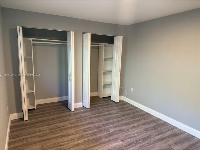 an empty room with wooden floor & closet area