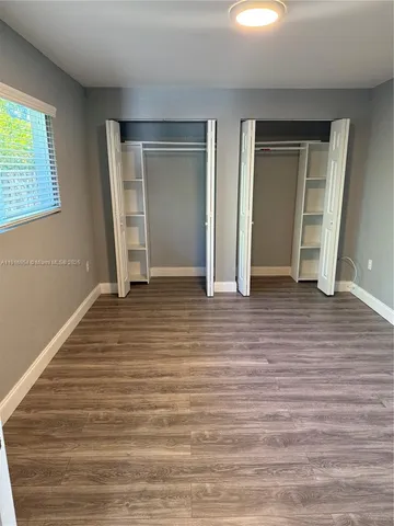 a view of empty room with window and wooden floor