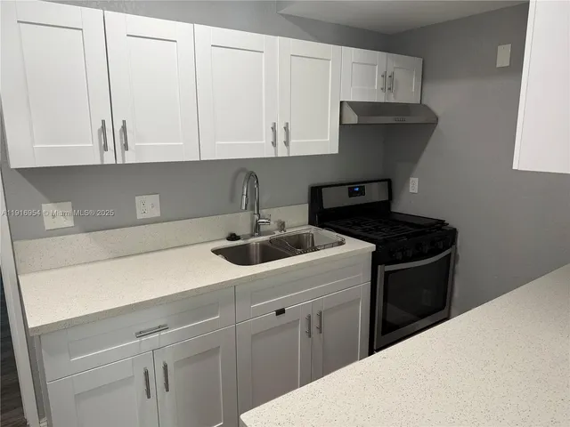 a kitchen with granite countertop white cabinets and a sink