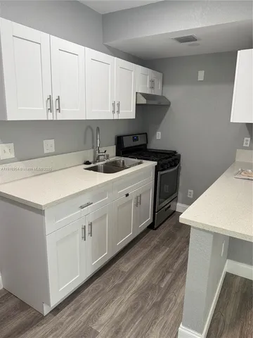a kitchen with stainless steel appliances granite countertop a stove a sink and white cabinets
