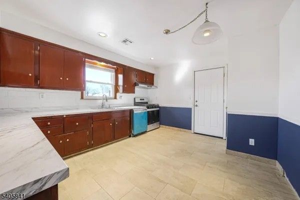 a kitchen with stainless steel appliances granite countertop a sink a stove a refrigerator cabinets and a window