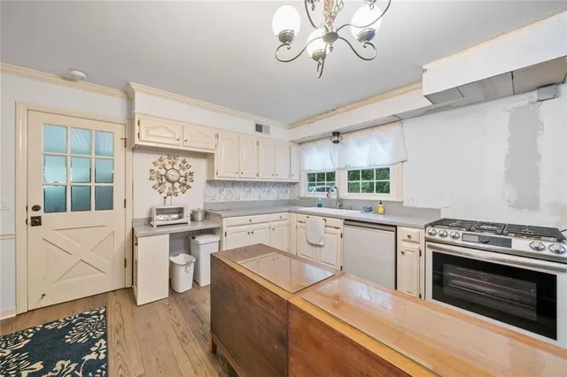 a kitchen with stainless steel appliances a stove top oven a sink dishwasher and a refrigerator with wooden floor