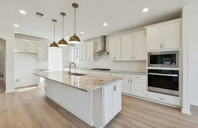 a kitchen with stainless steel appliances granite countertop a sink a stove and a wooden floors