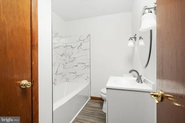 a bathroom with a sink and mirror with bathtub