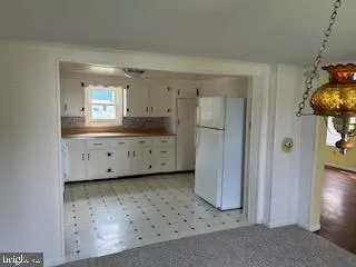 a kitchen with granite countertop white cabinets and refrigerator