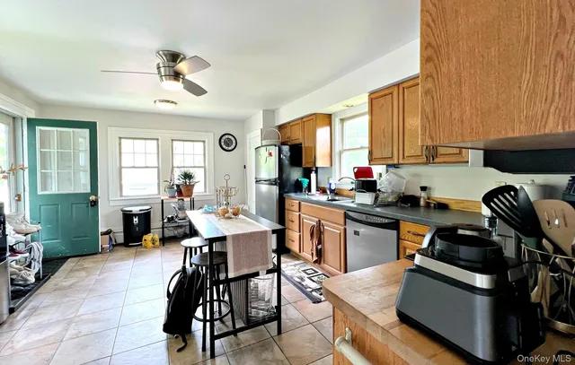 a kitchen with a stove a sink dishwasher a dining table and chairs with wooden floor