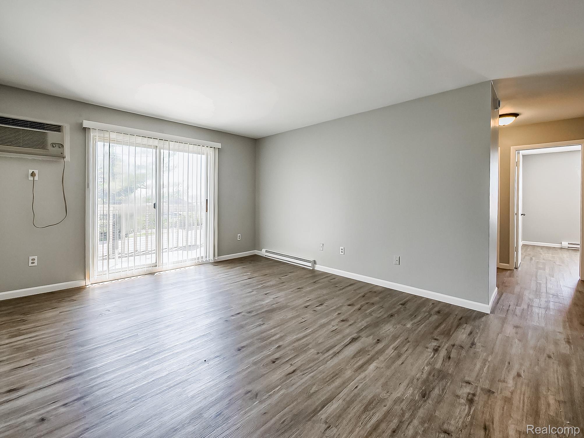 125 East Van Riper Road, Unit 5 Fowlerville, MI 48836 - Photo 4 of 23 Unfurnished room with dark wood-type flooring and a baseboard radiator