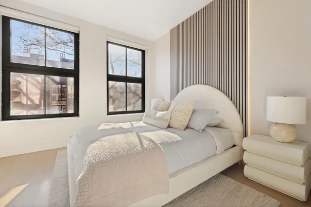 a large white bed sitting in a bedroom next to a lamp
