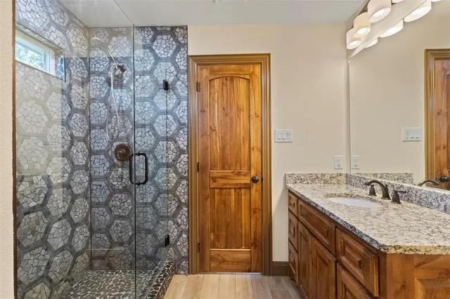 a bathroom with a granite countertop shower a sink and a mirror