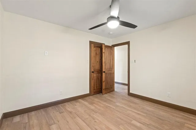 an empty room with wooden floor and a ceiling fan