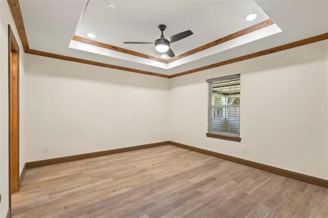 a view of empty room with wooden floor and fan