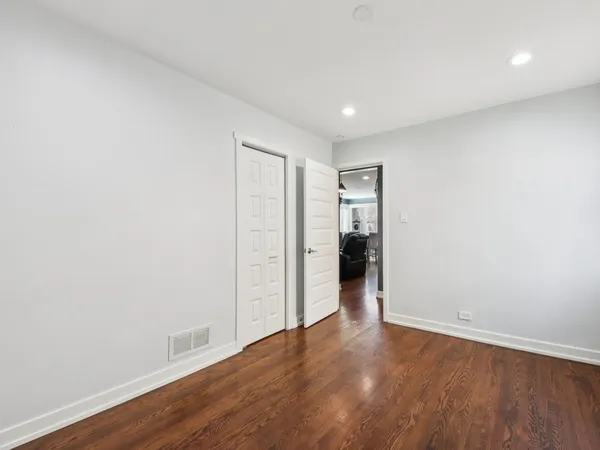a view of an empty room with wooden floor & closet