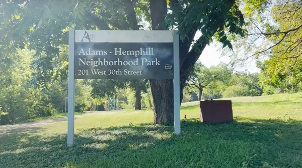 a sign that is sitting in front of a tree