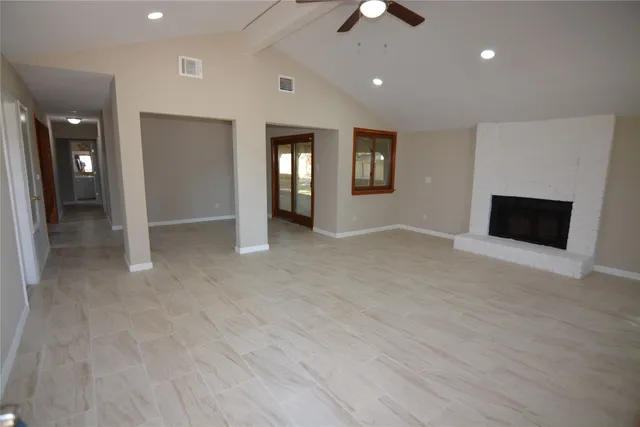 an empty room with fan and way to kitchen