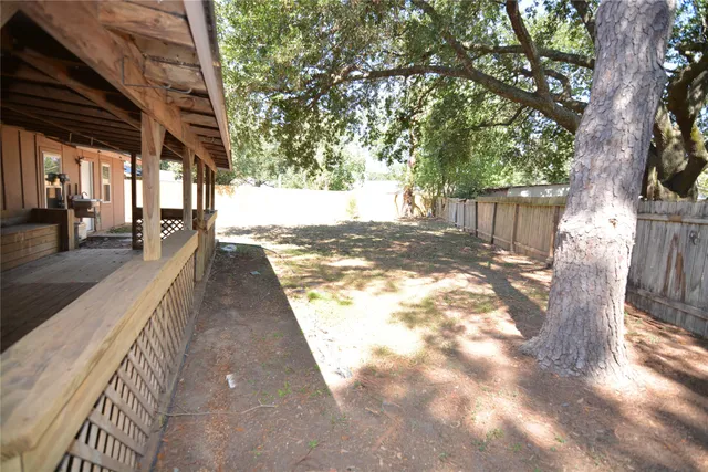 a view of a backyard with wooden fence and large trees