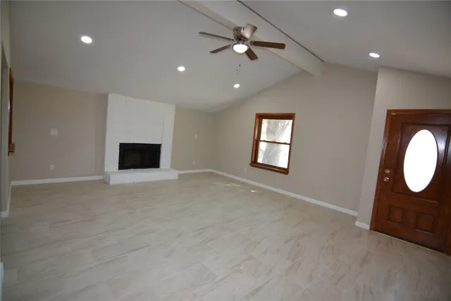 a view of an empty room with a fireplace and a window