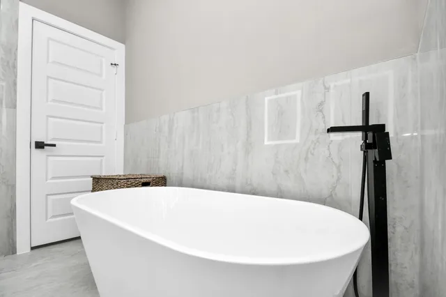 a bathroom with a tub a sink and mirror