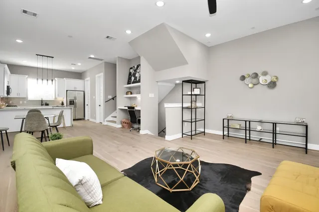 a living room with furniture kitchen view and a wooden floor