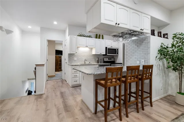 a kitchen with granite countertop white cabinets and stainless steel appliances