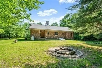 a view of a backyard with table and chairs plants and large trees