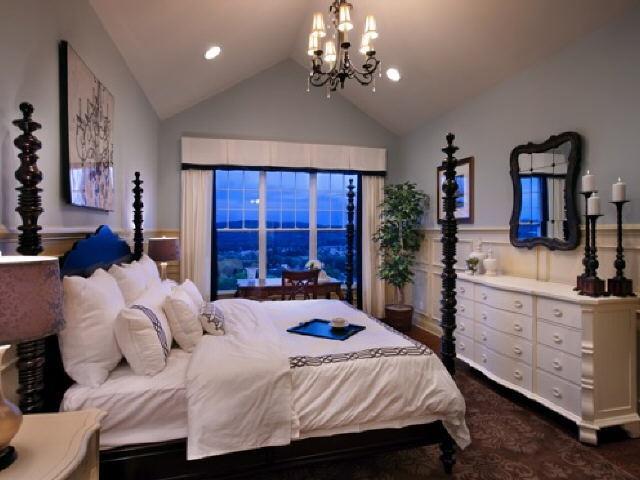 a bedroom with a large bed and dresser with mirror
