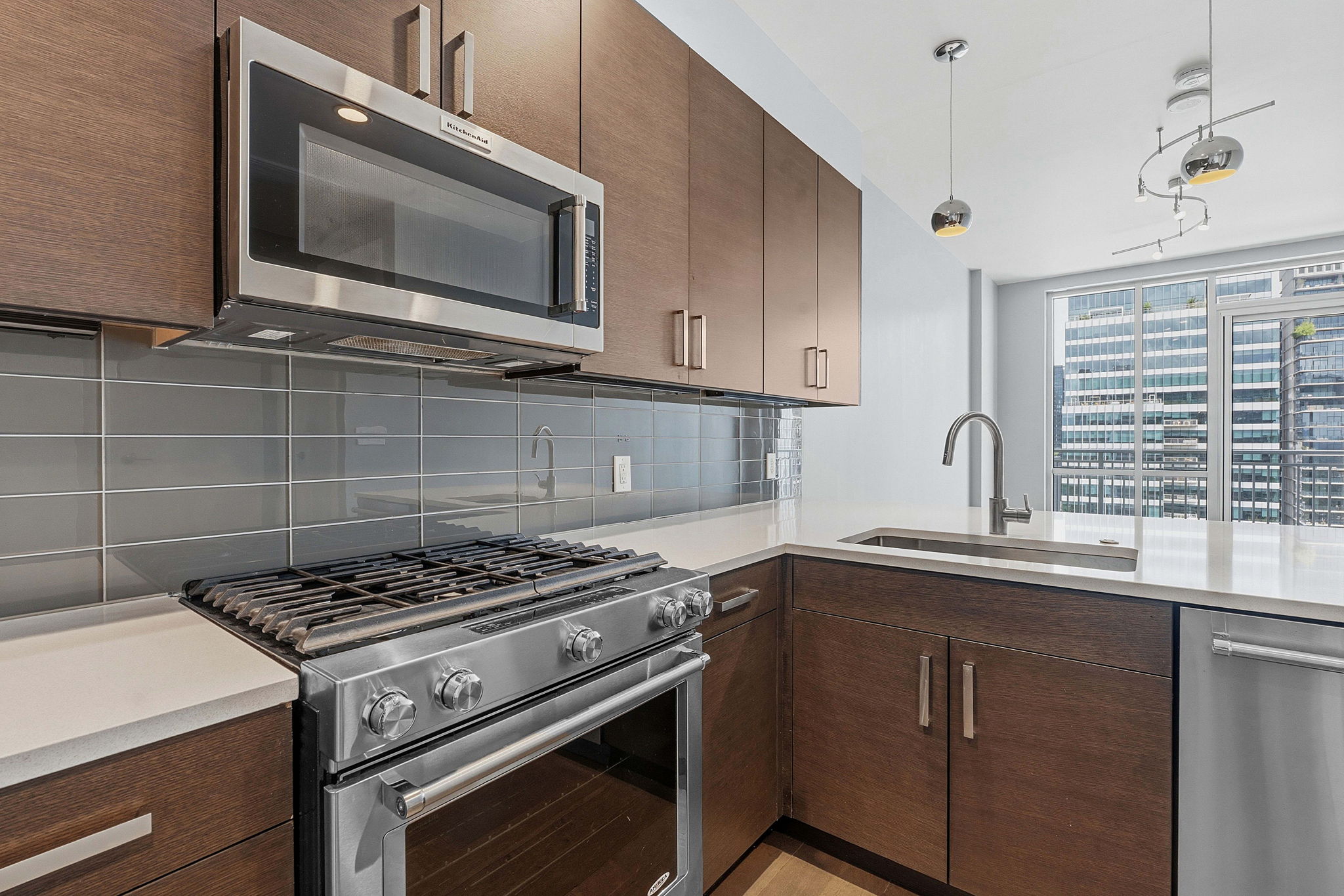 222 West Avenue, Unit 2207 Austin, TX 78701 - Photo 2 of 30 Modern kitchen featuring wood-finish cabinetry, stainless steel appliances, and light-toned countertops
