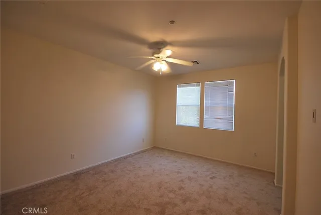 an empty room with a chandelier fan and windows