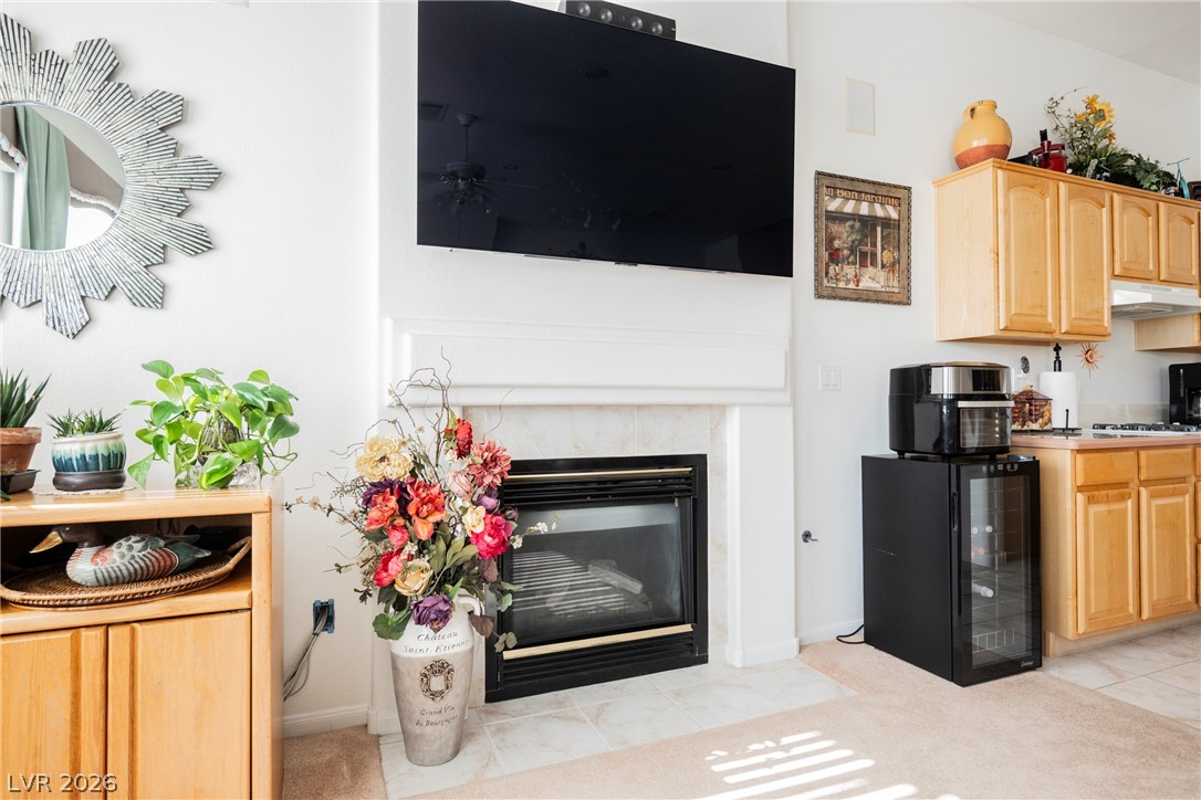 5494 Pine Ranch Street Las Vegas, NV 89113 - Photo 26 of 54 A cozy living space features a fireplace with a mantel, flowing into a kitchen with wooden cabinetry and a built-in cooktop.