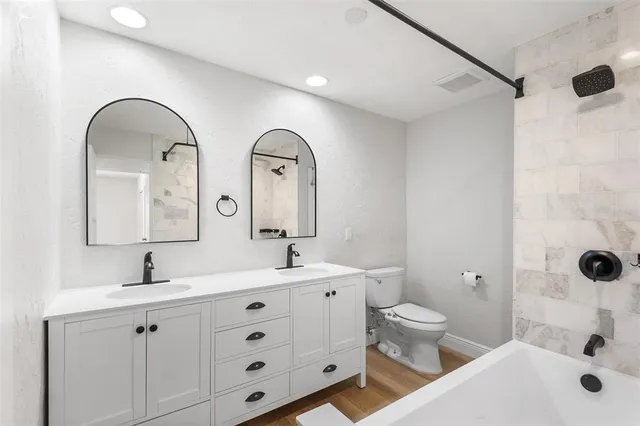 a bathroom with a double vanity sink toilet and shower