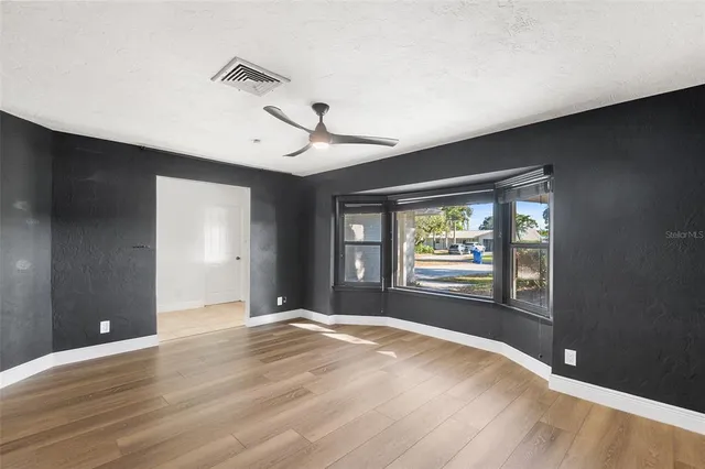 a view of an empty room with window and wooden floor
