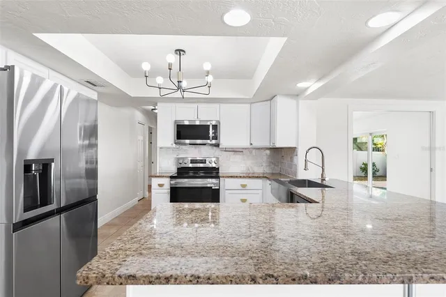 a kitchen with stainless steel appliances granite countertop a refrigerator a stove top oven a sink a dining table and chairs