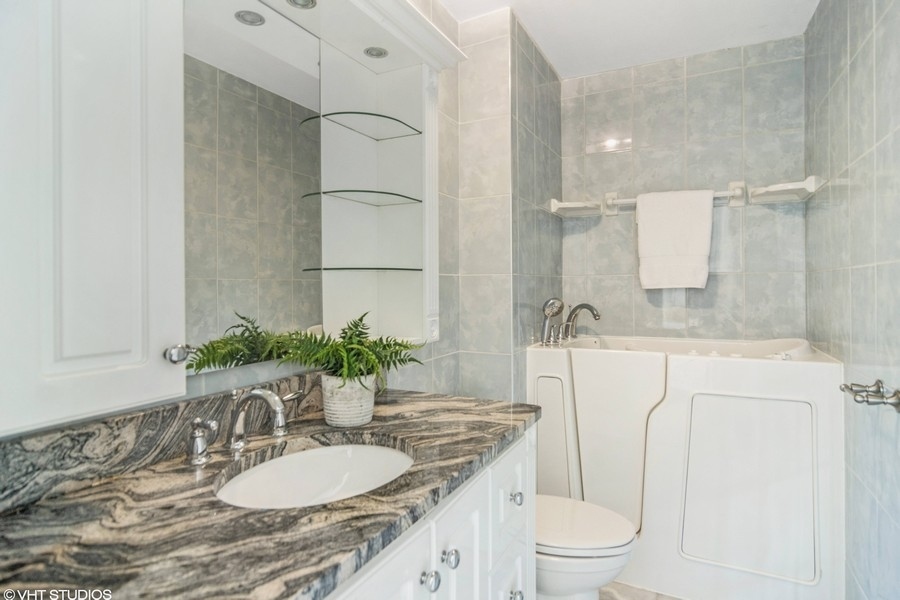 545 Greystone Lane, Unit A2 Wheeling, IL 60090 - Photo 11 of 21 a bathroom with a granite countertop sink a toilet a mirror and shower
