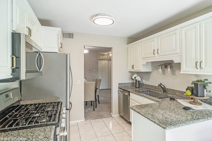 545 Greystone Lane, Unit A2 Wheeling, IL 60090 - Photo 4 of 21 a kitchen with stainless steel appliances granite countertop a sink stove and refrigerator