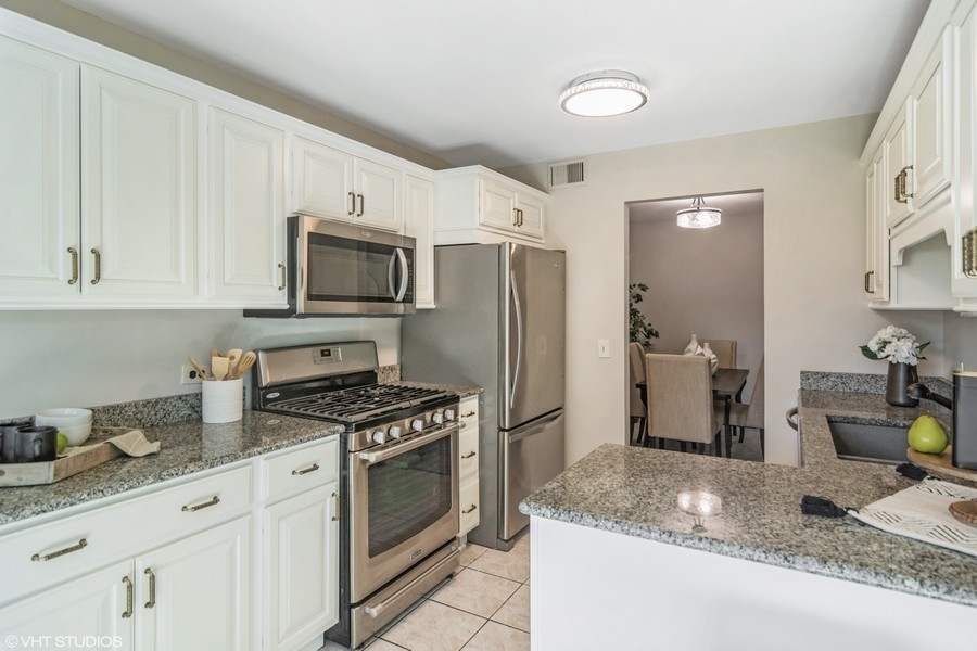 545 Greystone Lane, Unit A2 Wheeling, IL 60090 - Photo 5 of 21 a kitchen with granite countertop a sink stove and refrigerator