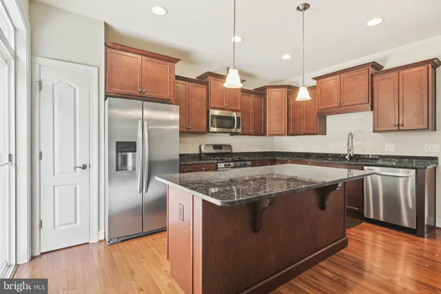 a kitchen with stainless steel appliances granite countertop a refrigerator a sink and a stove