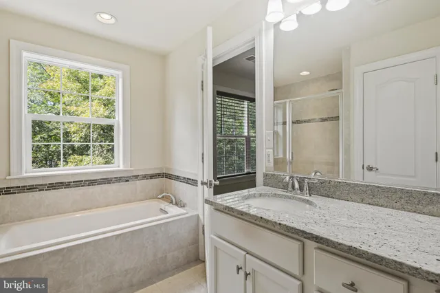 a bathroom with a granite countertop tub sink and mirror