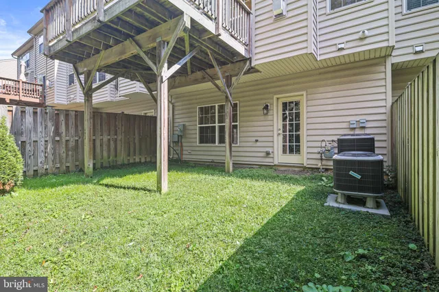 a backyard of a house with wooden fence and a large tree