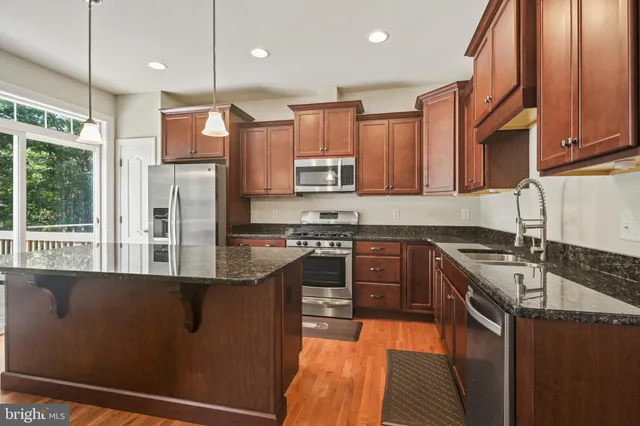 a kitchen with stainless steel appliances granite countertop a refrigerator a stove a sink and a microwave