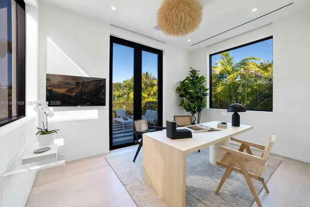 a living room with stainless steel appliances furniture a flat screen tv and a large window