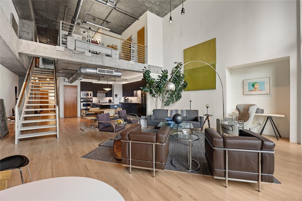 2011 Cedar Springs Road, Unit 305 Dallas, TX 75201 - Photo 12 of 27 Spacious open-concept living area featuring high ceilings, wood-finish flooring, and exposed concrete architectural elements