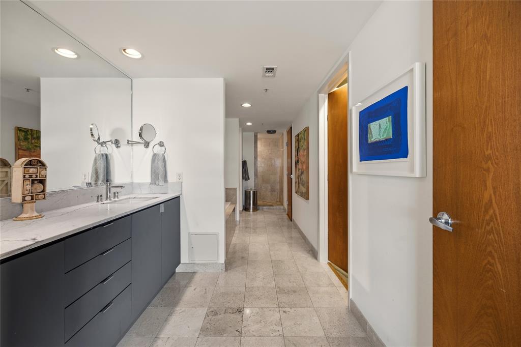 2011 Cedar Springs Road, Unit 305 Dallas, TX 75201 - Photo 21 of 27 Bathroom corridor featuring a floating vanity with a light-colored countertop, integrated sink, and dual mirrors