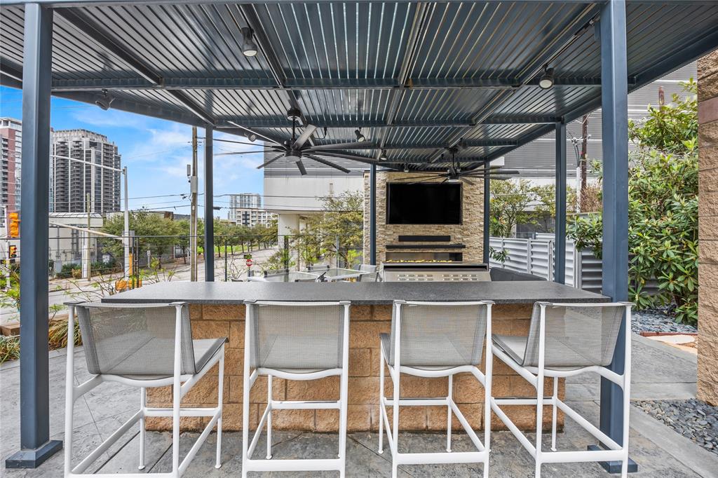 2011 Cedar Springs Road, Unit 305 Dallas, TX 75201 - Photo 25 of 27 Covered outdoor bar area featuring a built-in television, fireplace, and two ceiling fans