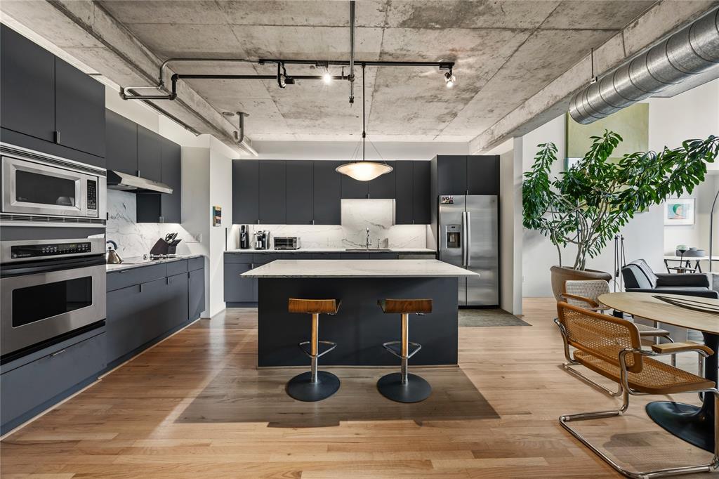 2011 Cedar Springs Road, Unit 305 Dallas, TX 75201 - Photo 6 of 27 Modern kitchen featuring dark cabinetry, stainless steel appliances, and light wood-finish flooring