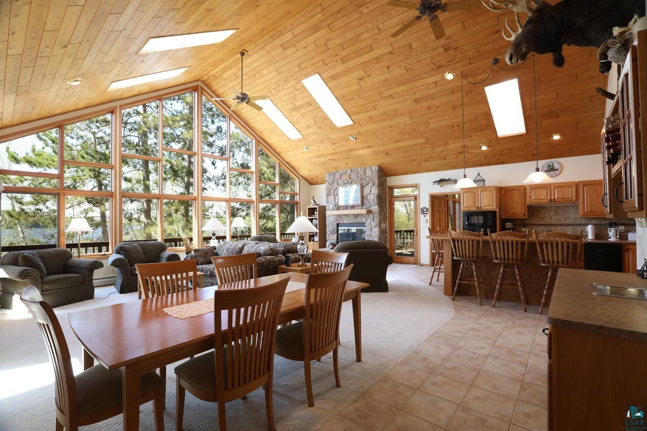 1880 Everett Bay Road Tower, MN 55790 - Photo 5 of 50 Dining space featuring a skylight, high vaulted ceiling, ceiling fan, a fireplace, and light tile patterned floors
