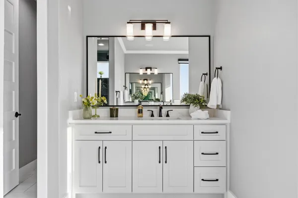 a bathroom with white cabinets and a mirror