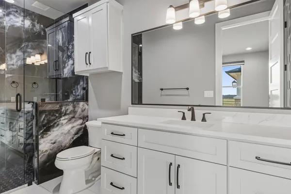 a bathroom with a sink a toilet and shower