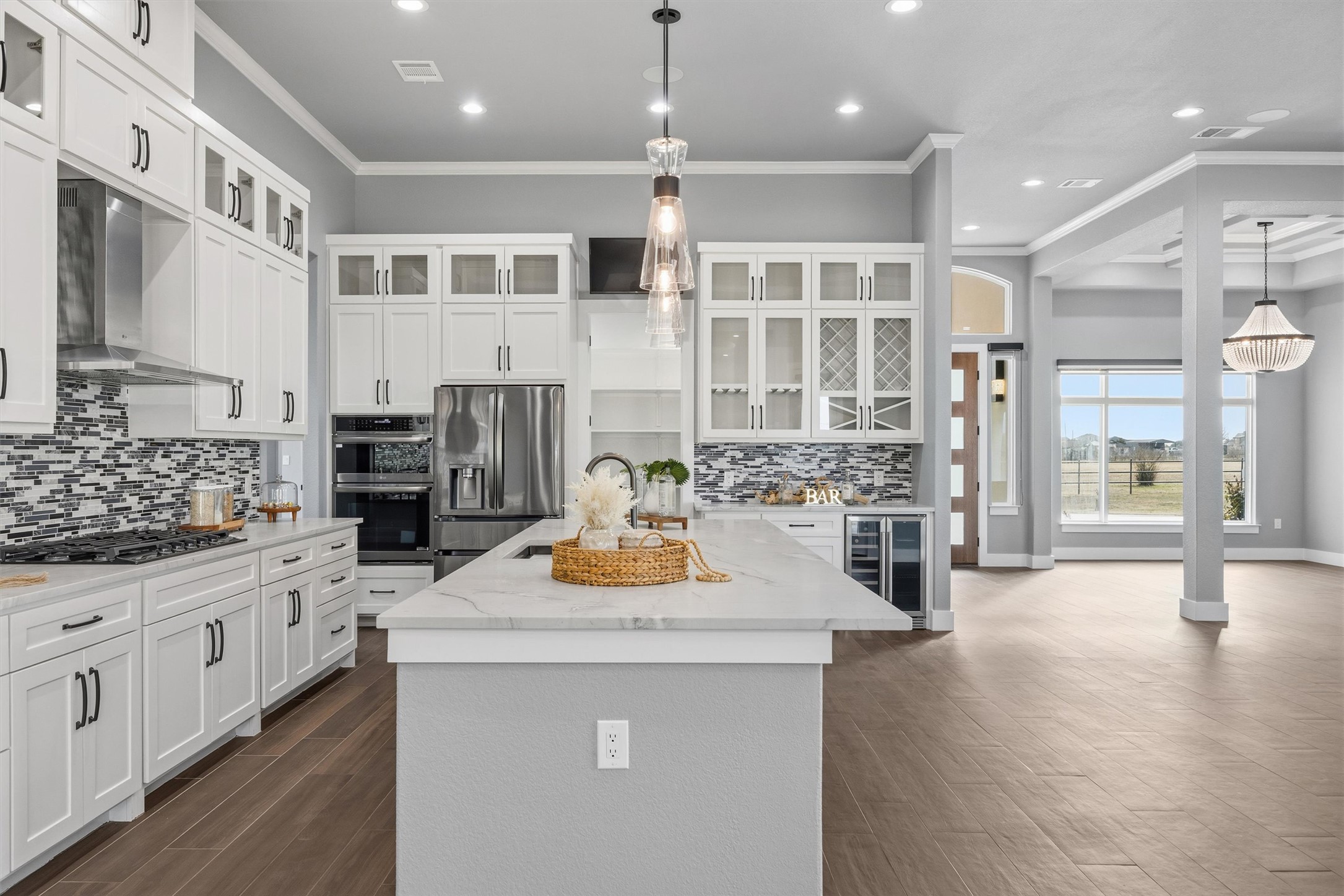 178 Balch Road Elgin, TX 78621 - Photo 9 of 40 Kitchen featuring glass insert cabinets, light stone countertops, hanging light fixtures, and ornamental molding